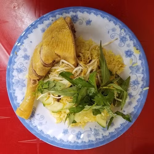 Phần đùi gà chín vàng được xếp cùng cơm, trang trí rau dăm, giá, hành củ muối. Ảnh: Tung Nguyen.