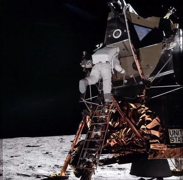 Phi hành gia Buzz Aldrin, người lái Eagle hạ cánh xuống Mặt Trăng cùng Armstrong, đang bước xuống thang để cùng Armstrong bước đi trên Mặt Trăng. Armstrong chụp vài chục ảnh của Aldrin trên Mặt Trăng, nhưng Armstrong hầu như không được ai chụp ảnh. Ảnh: NASA.