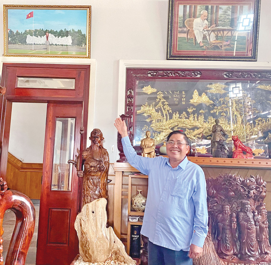 Nguyên Bí thư Tỉnh ủy Hà Sơn Nhin chỉ về bức ảnh chụp Tượng đài Bác Hồ với các dân tộc Tây Nguyên được treo trang trọng nơi phòng khách gia đình ông. Ảnh: Hồng Thi