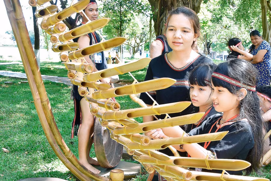 Chị R’Com H’Sonh dạy con gái đánh đàn t'rưng. Ảnh: Đức Thụy