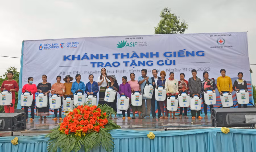 Hoa hậu H’Hen Niê(thứ 7 từ trái sang)-đại sứ Nhân ái của tổ chức ASIF trao tặng gùi nước cho bà con. Ảnh: Hoàng Cư