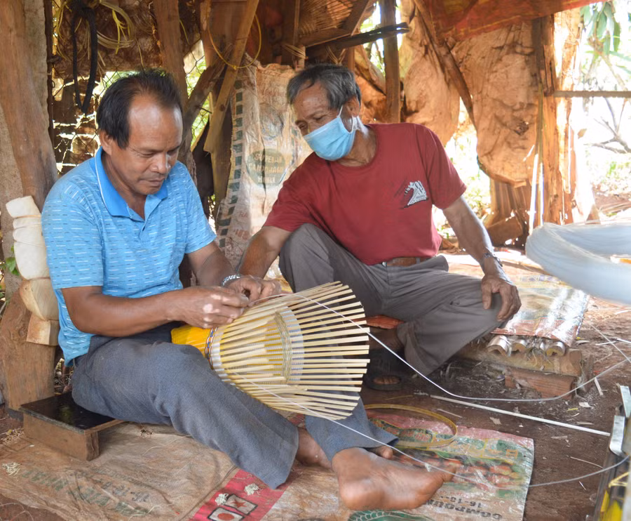 Già làng Sêl (bìa phải; làng Ngơm Thung, xã Ia Pết, huyện Đak Đoa) hướng dẫn người dân đan gùi để tăng thu nhập, giữ gìn nghề truyền thống. Ảnh: Anh Huy