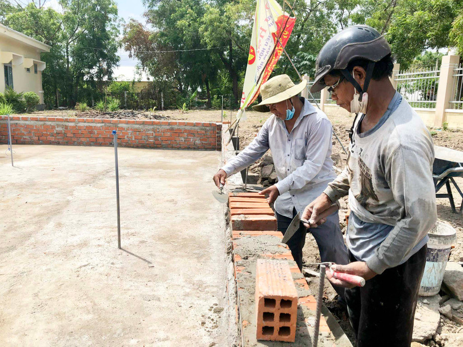 Ông Ksor Dung (bìa phải) giúp Trường Tiểu học Trần Quốc Tuấn xây dựng công trình biển đảo quê hương. Ảnh: Gia Hưng