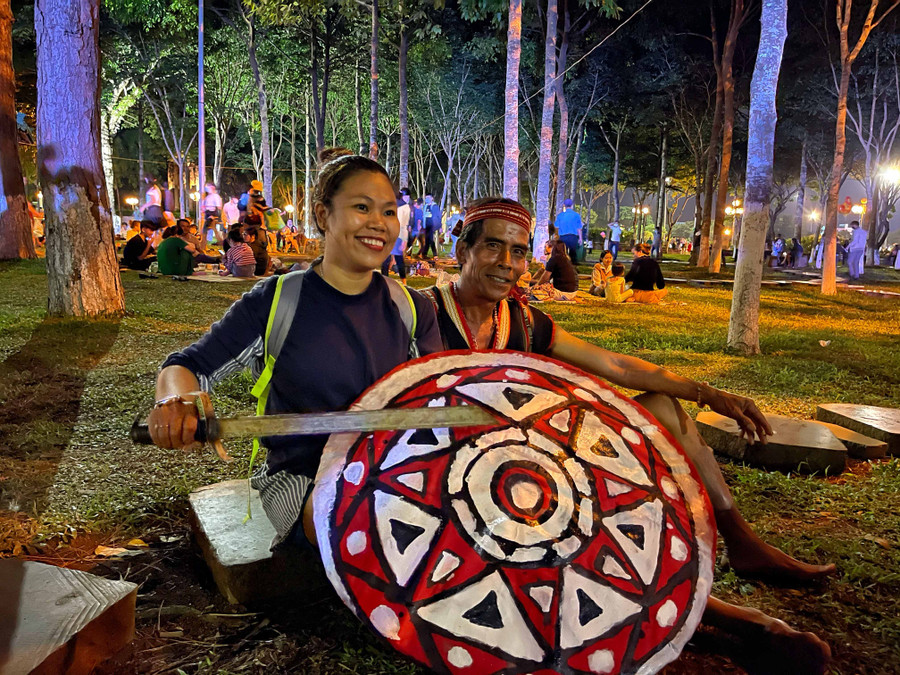 Một nữ du khách thích thú khi được hướng dẫn cách cầm khiên và kiếm văn hóa của người Bahnar