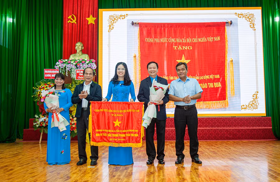  Hai đồng chí Hồ Văn Niên-Bí thư Tỉnh ủy (bìa phải) và Võ Ngọc Thành (thứ hai từ trái qua)-Chủ tịch UBND tỉnh trao cờ thi đua xuất sắc của Chính phủ cho LĐLĐ tỉnh tại lễ tuyên dương. Ảnh: Đinh Yến