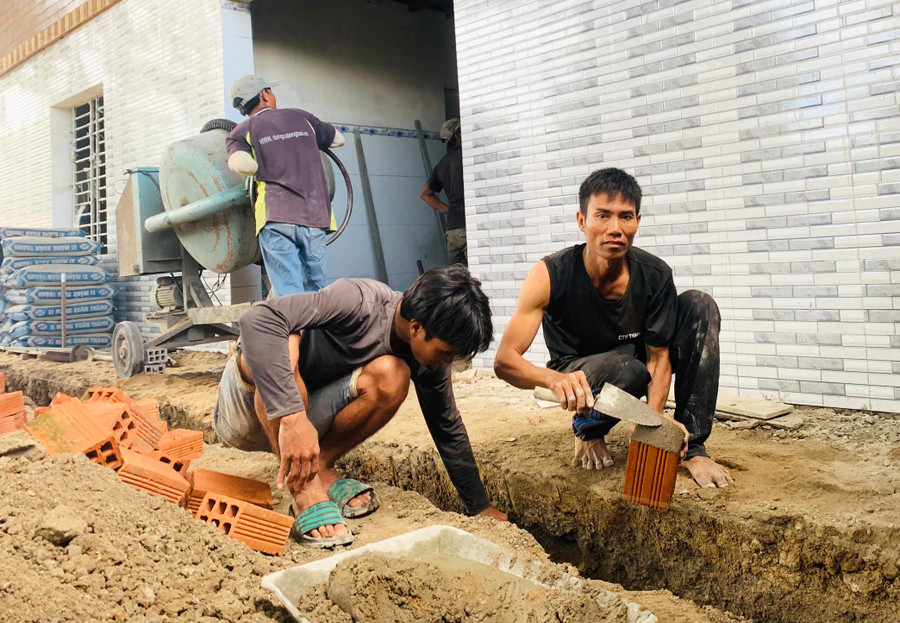 Anh Ksor Duy (bìa phải, buôn Toát, xã Ia Rsươm, huyện Krông Pa) xây bậc tam cấp cho căn nhà mới của mình. Ảnh: Nguyên Hương