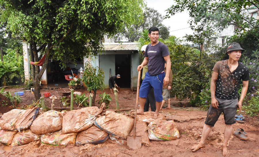 Anh Mai Tiến Vũ (xã Kdang) cùng người thân trong gia đình dọn dẹp bùn đất tràn vào nhà. Ảnh: Hà Phương