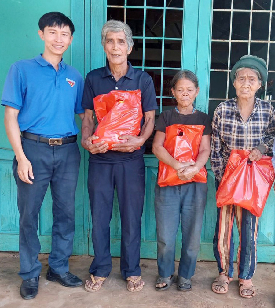  Anh Nguyễn Cảnh Bá (bìa trái) tặng quà cho các gia đình có hoàn cảnh khó khăn trên địa bàn xã Kon Thụp. Ảnh: Hà Phương