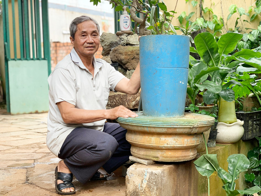  Ông Phùng Xuân Minh (làng Ngó, phường Trà Bá, TP. Pleiku) bên nửa quả bom được tháo kíp nổ, sơn màu làm chậu trồng hoa. Ảnh: Nhật Hào