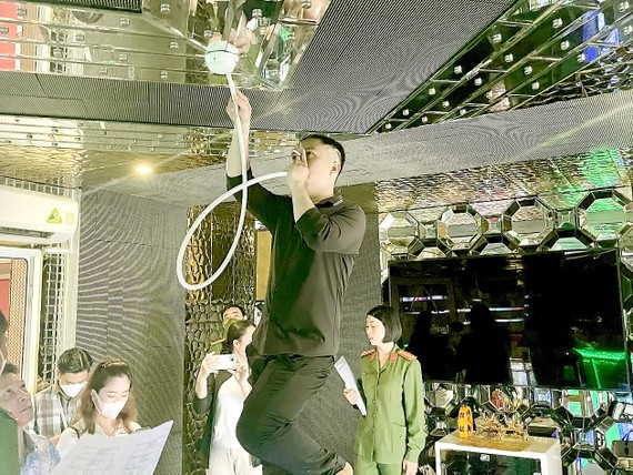 Nhân viên của cơ sở kinh doanh karaoke F YOU II thử thiết bị báo nhiệt theo yêu cầu của đoàn kiểm tra. Ảnh: Thục Hân