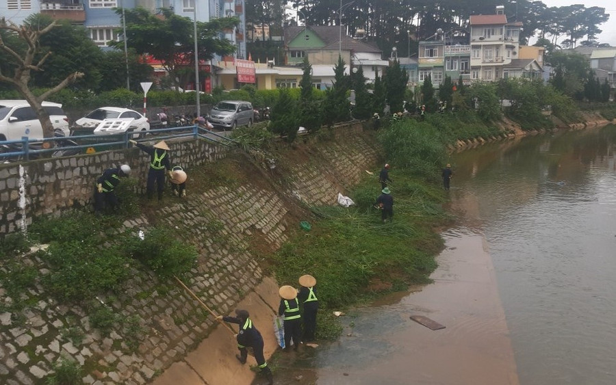 Công nhân Công ty Cổ phần Dịch vụ đô thị Đà Lạt dọn dẹp cây cỏ dọc suối Cam ly. Ảnh: LV