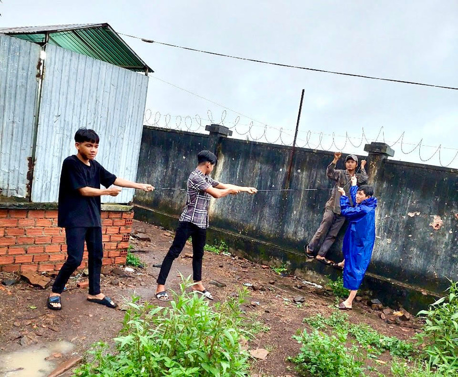 Giáo viên cùng học sinh Trường THCS Dân tộc Nội trú huyện Chư Pưh cột giữ mái che của nhà vệ sinh học sinh để tránh gió bão làm tốc mái. Ảnh: Mộc Trà