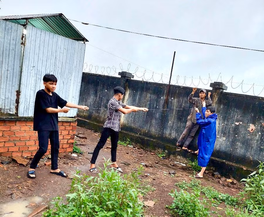 Giáo viên cùng học sinh Trường THCS Dân tộc Nội trú huyện Chư Pưh cột giữ mái che của nhà vệ sinh học sinh để tránh gió bão làm tốc mái. Ảnh: Mộc Trà