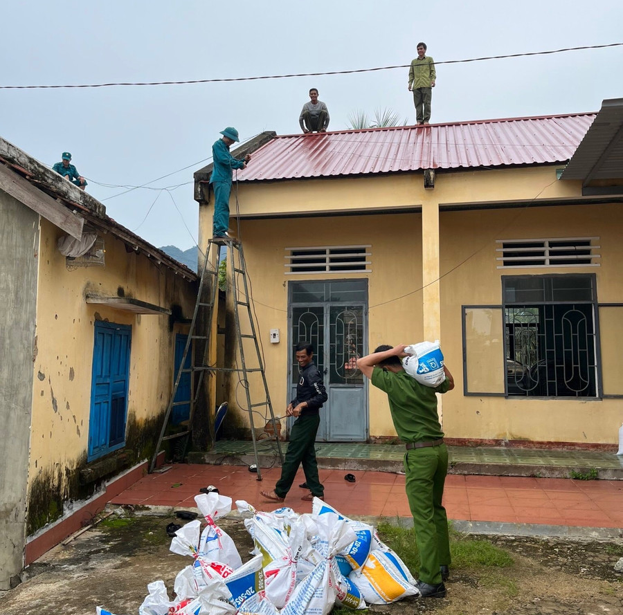 Lực lượng Công an, dân quân giúp người dân xã Lơ Ku, huyện Kbang chặn những bao cát trên mái nhà, hạn chế tốc mái. Ảnh: An Phát