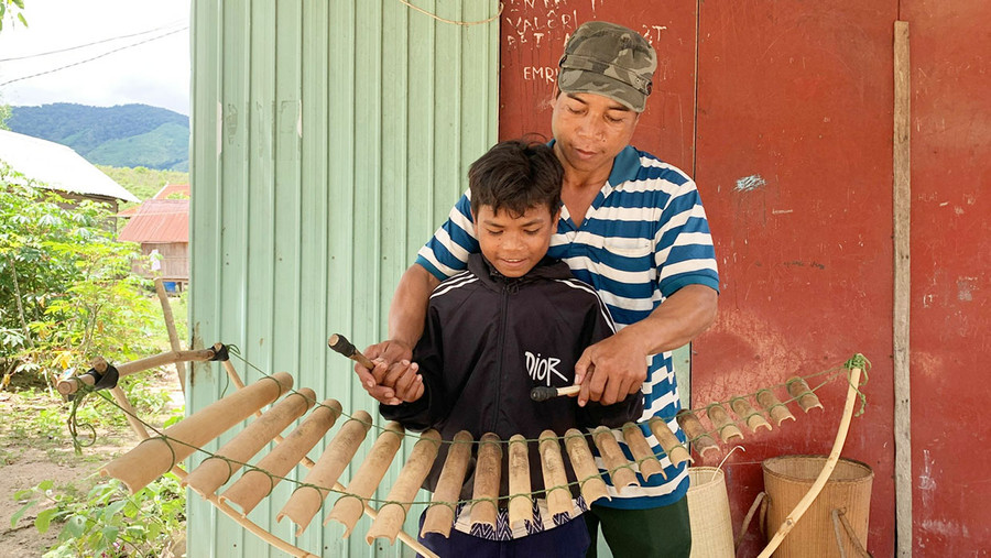 Nghệ nhân Đinh Thây truyền dạy cách đánh đàn trưng cho thiếu nhi làng Kte Kchăng, xã Đak Song, huyện Kông Chro. Ảnh: R'Ô HOK