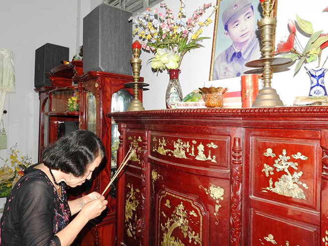 Bà Mai trước bàn thờ của chồng mình.