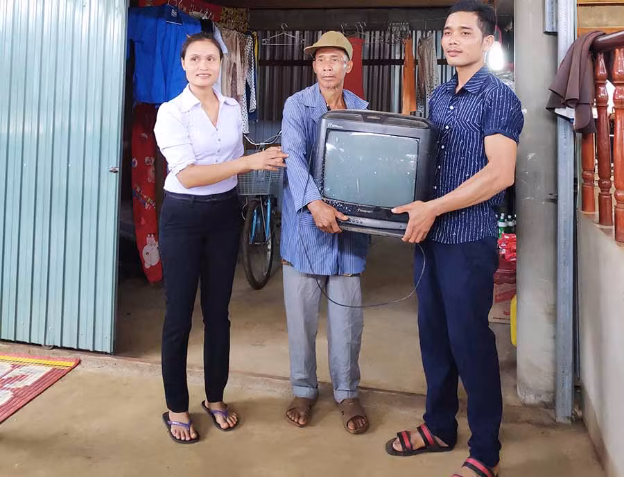  Chị Rơ Chăm H'Ken (bìa trái) tặng ti vi cho ông Rơ Chăm Sép. Ảnh: H.U