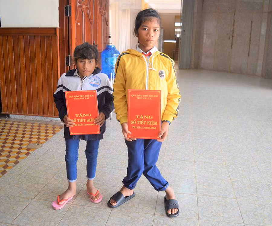  Em Brếp (trái) và Rah Lan HHương nhận sổ tiết kiệm do Quỹ Bảo trợ trẻ em tỉnh tặng. Ảnh: Đ.Y