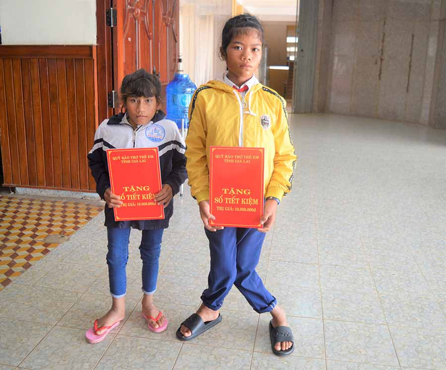  Em Brếp (trái) và Rah Lan HHương nhận sổ tiết kiệm do Quỹ Bảo trợ trẻ em tỉnh tặng. Ảnh: Đ.Y