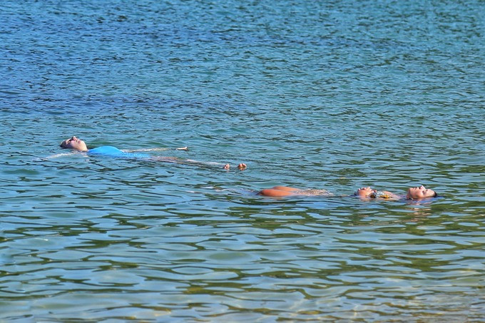 Du khách thoải mái trong làn nước mát lạnh, trong xanh của bãi biển làng chài.