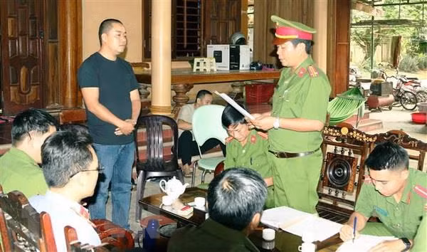  Lực lượng Công an tống đạt các quyết định khởi tố vụ án, khởi tố bị can và Lệnh tạm giam đối với Đinh Ngọc Tý. (Ảnh: Quang Văn/TTXVN phát)