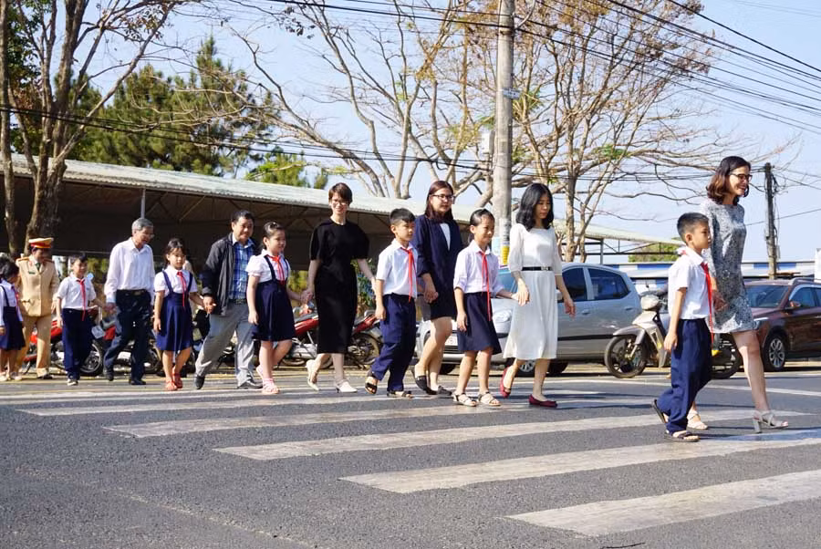 Thành viên dự án hướng dẫn học sinh qua đường an toàn. Ảnh: L.H