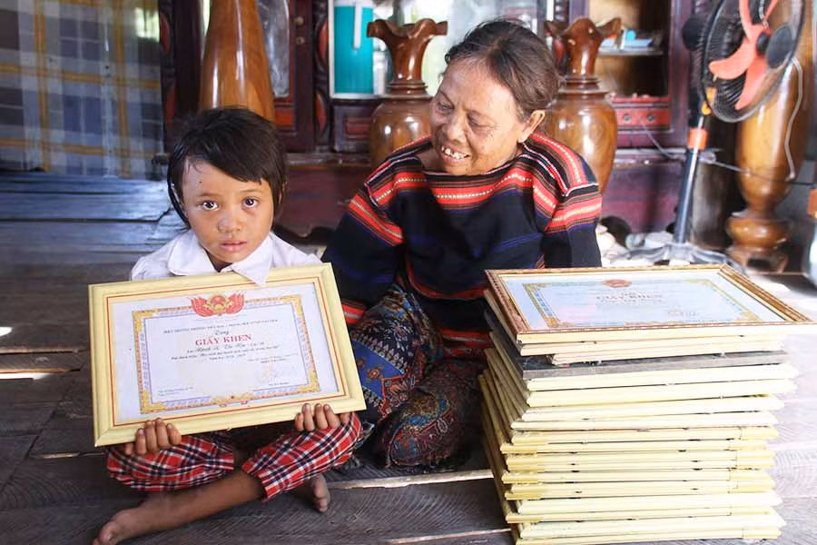 Bà Rmah H'Đoan khoe giấy khen và thành tích học tập của con cháu. Ảnh: P.N Bà Rmah H'Đoan khoe giấy khen và thành tích học tập của con cháu. Ảnh: P.N