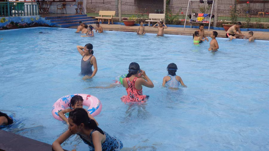 Các anh chị đoàn viên hướng dẫn cho các em kỹ năng học bơi. Ảnh: Hà Phương