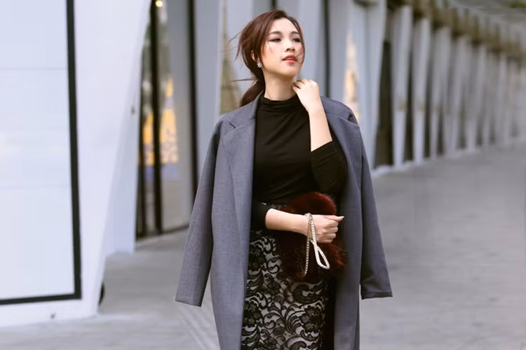 Á hậu phối áo khoác dáng dài, áo cổ lọ cùng chân váy ren họa tiết hoa 3D sang trọng tạo nên một set đồ monochrome thời thượng. Chiếc túi xách lông màu đỏ cũng là một phụ kiện yêu thích của nhiều tín đồ thời trang trong năm vừa qua.