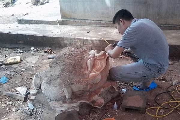 Một thợ đang tạo hình cóc từ một khối gỗ nu. Ảnh: Lê Hòa
