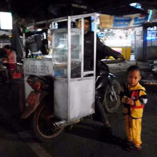 Cậu bé lên 3 theo cha đi bán cá viên chiên. Ảnh: Trần Dung