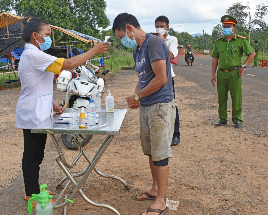Chị Kpuih H’Phinh đo thân nhiệt cho những người đi qua chốt. Ảnh: Hà Phương