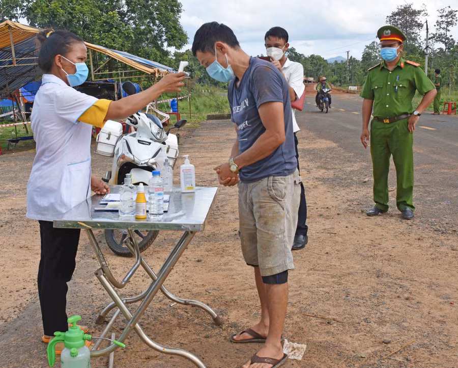 Chị Kpuih H’Phinh đo thân nhiệt cho những người đi qua chốt. Ảnh: Hà Phương