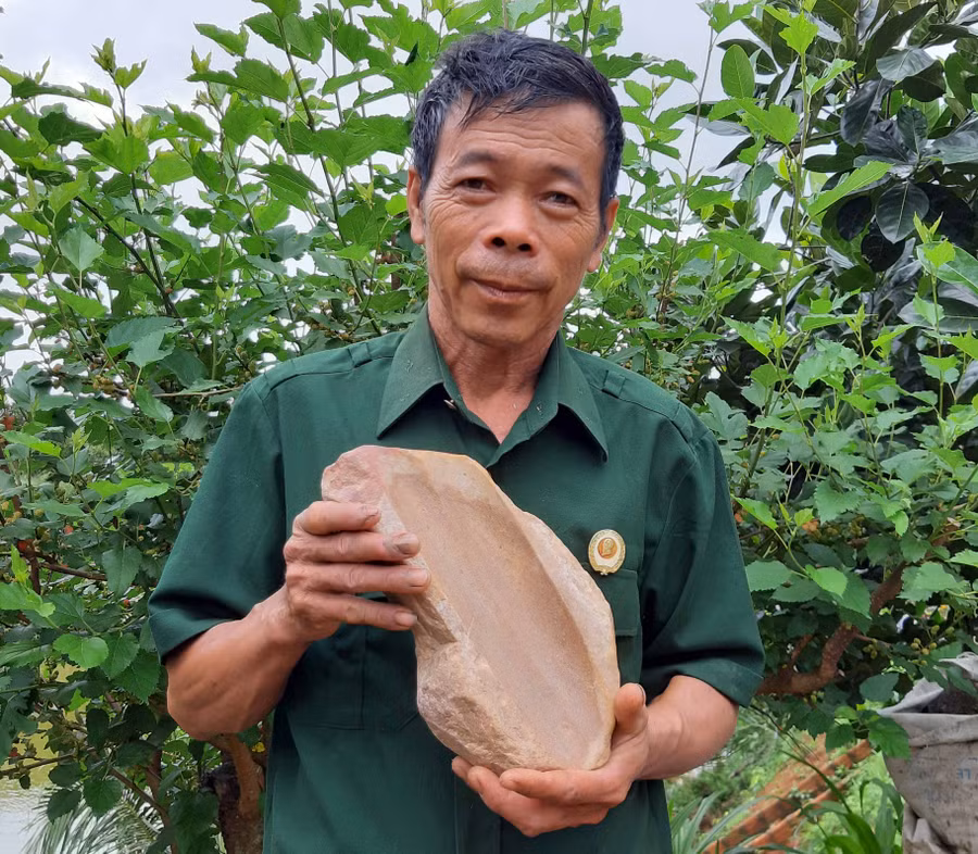 Ông Đặng Thanh Vân và bàn mài đá có niên đại cách nay 4.000-3.500 năm. Ảnh: Nguyễn Quang Tuệ