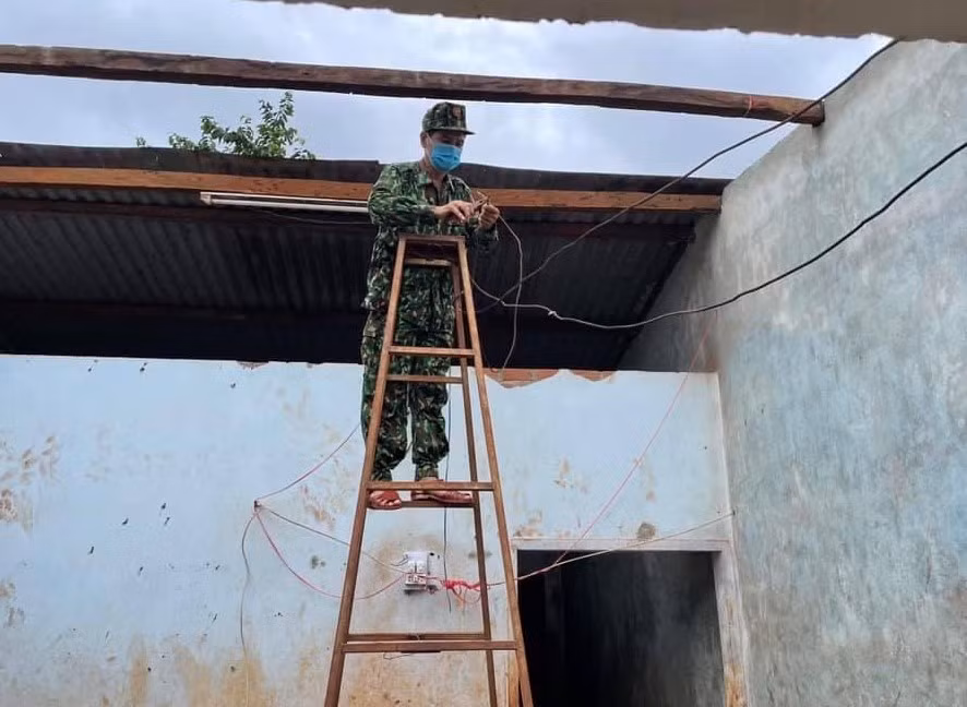 Cán bộ Đồn Biên phòng Ia Chía tham gia lợp lại mái tôn cho gia đình bà Phyơ. Ảnh: Anh Huy