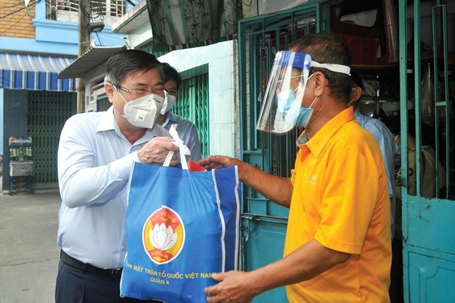 Chủ tịch UBND TPHCM Nguyễn Thành Phong (trái) tặng quà cho người dân khó khăn vì dịch COVID-19. Ảnh: Cao Thăng