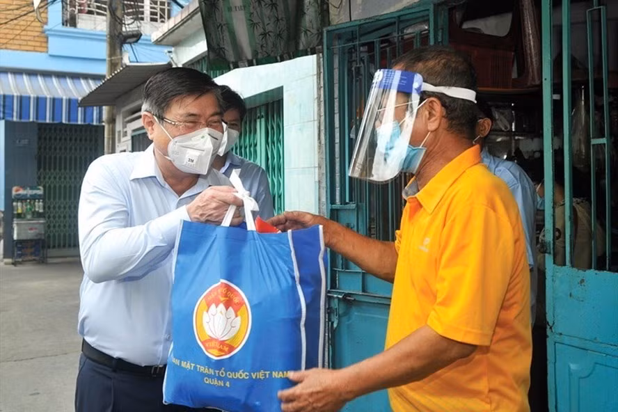 Chủ tịch UBND TPHCM Nguyễn Thành Phong (trái) tặng quà cho người dân khó khăn vì dịch COVID-19. Ảnh: Cao Thăng