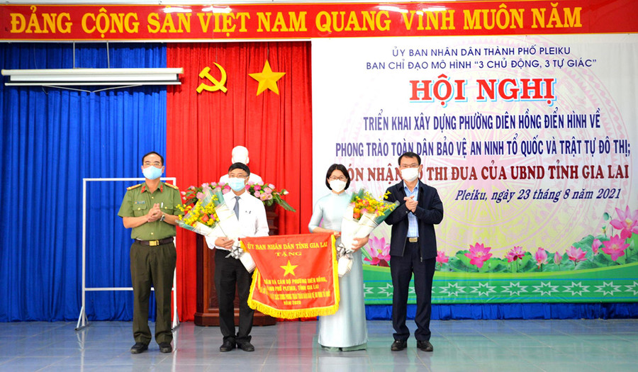 Đại tá Phạm Hữu Trường-Phó Giám đốc Công an tỉnh và Bí thư Thành ủy Pleiku Trịnh Duy Thuân trao cờ thi đua xuất sắc trong phong trào “Toàn dân bảo vệ an ninh Tổ quốc” năm 2020 của UBND tỉnh cho phường Diên Hồng. Ảnh: Nguyễn Hữu