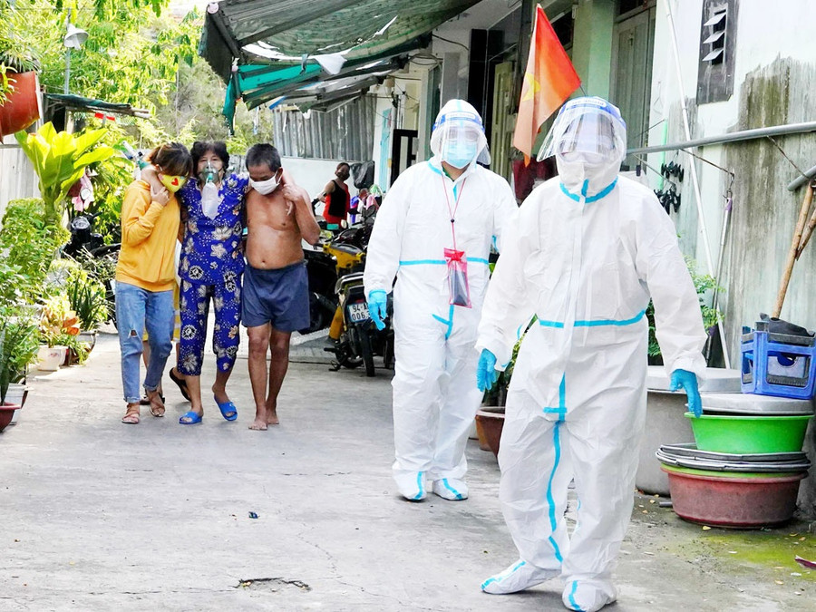 Sau khi xách đồ đạc của bệnh nhân ra khử khuẩn, ông Dũng và Minh Hoàng quay trở lại để dìu bệnh nhân, nhưng người thân của F0 xin tự dìu để hạn chế lây nhiễm. Ảnh: Độc Lập 