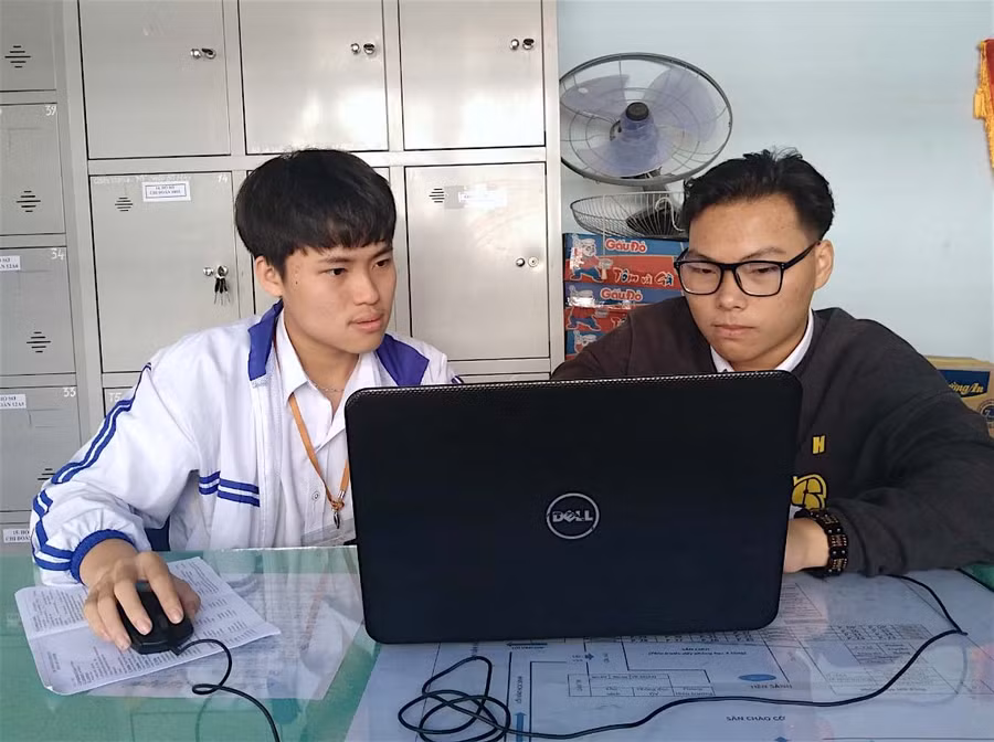 Em Tạ Quang Huy (bìa trái) và Lê Trần Anh Tài (lớp 12D1, Trường THPT Pleiku) hỗ trợ nhau viết phần mềm điều khiển cho xe lăn (ảnh chụp tháng 1-2021). Ảnh: Mộc Trà
