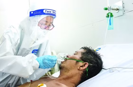 Nữ điều dưỡng (Khu điều trị Covid-19 dã chiến Bệnh viện đa khoa Xuyên Á, Củ Chi, TPHCM) bón thuốc cho bệnh nhân đang điều trị. Ảnh: HOÀNG HÙNG