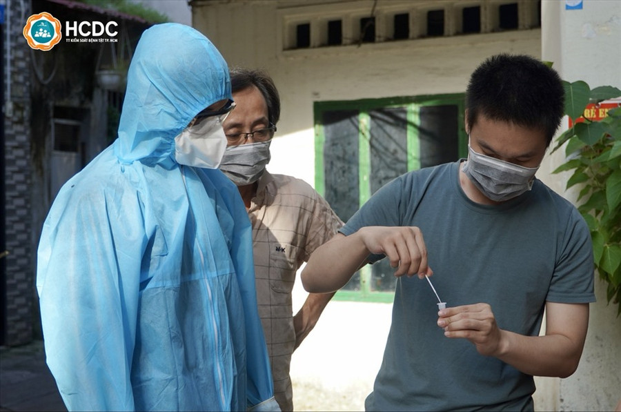 Người dân tự tay thực hiện lấy mẫu test nhanh cho người thân. Ảnh: HCDC
