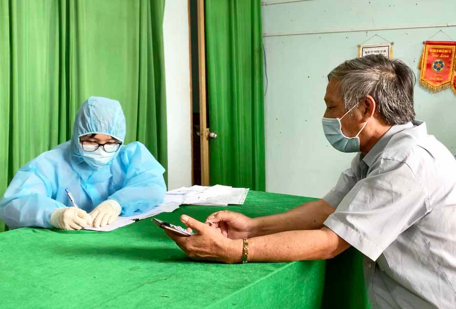 Nhân viên y tế lấy thông tin trước khi thực hiện lấy mẫu xét nghiệm cho người dân. Ảnh: Như Nguyện