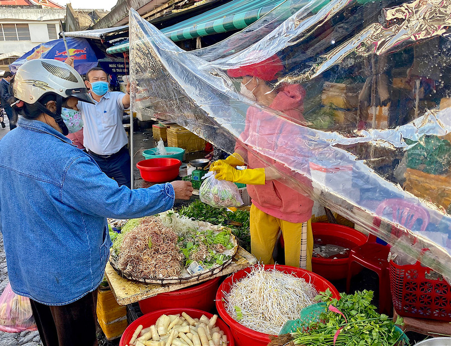 Ban Quản lý Trung tâm Thương mại TP. Pleiku hướng dẫn tiểu thương giăng bạt ni lông trước quầy hàng để hạn chế giọt bắn và tạo khoảng cách nhất định giữa người bán và người mua. Ảnh: Hồng Thi