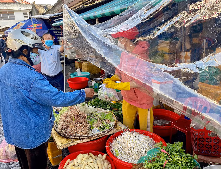 Ban Quản lý Trung tâm Thương mại TP. Pleiku hướng dẫn tiểu thương giăng bạt ni lông trước quầy hàng để hạn chế giọt bắn và tạo khoảng cách nhất định giữa người bán và người mua. Ảnh: Hồng Thi