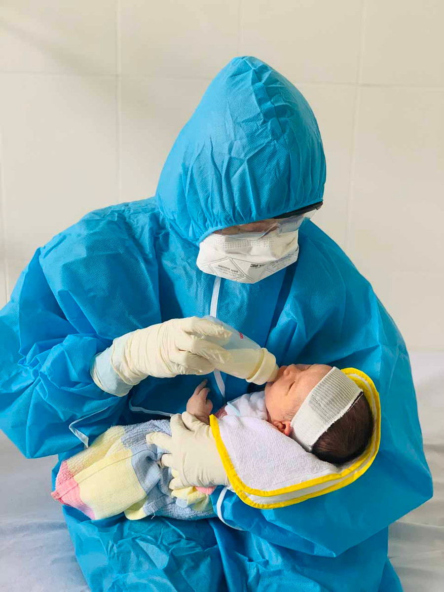 10-8-2021Nhân viên y tế Bệnh viện Nhi Gia Lai thay phiên chăm sóc cho bé trai con sản phụ F0. Ảnh Như Nguyện