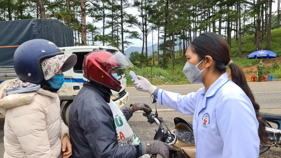 Cán bộ y tế đo thân nhiệt người dân trước khi qua chốt kiểm dịch Covid-19. Ảnh: Lâm Viên