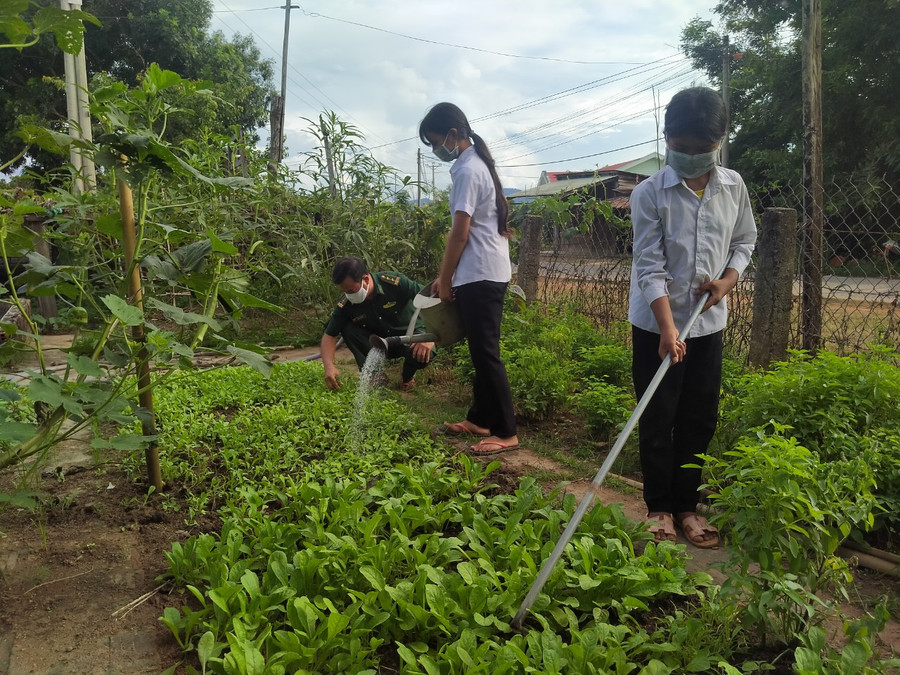 Rơ Lan Hi (cầm cuốc) chăm sóc vườn rau. Ảnh: Thiên Thanh