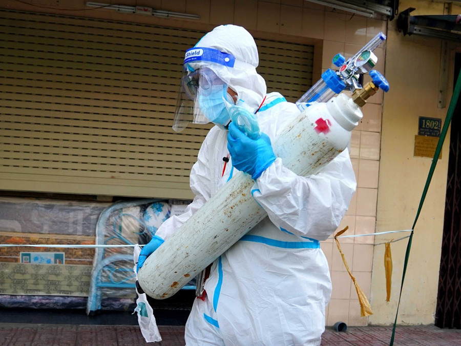 Xe taxi vừa dừng lại, Minh Hoàng vội vàng ôm bình ô xy chạy vào hẻm để cấp cứu bệnh nhân. Ảnh: Độc Lập