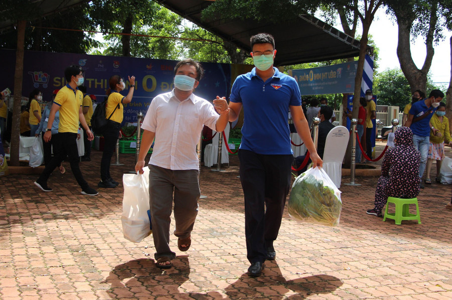Anh Báu, một người khiếm thị, được tình nguyện viên đi chợ giùm và dẫn ra về. Ảnh: Hoàng Bình